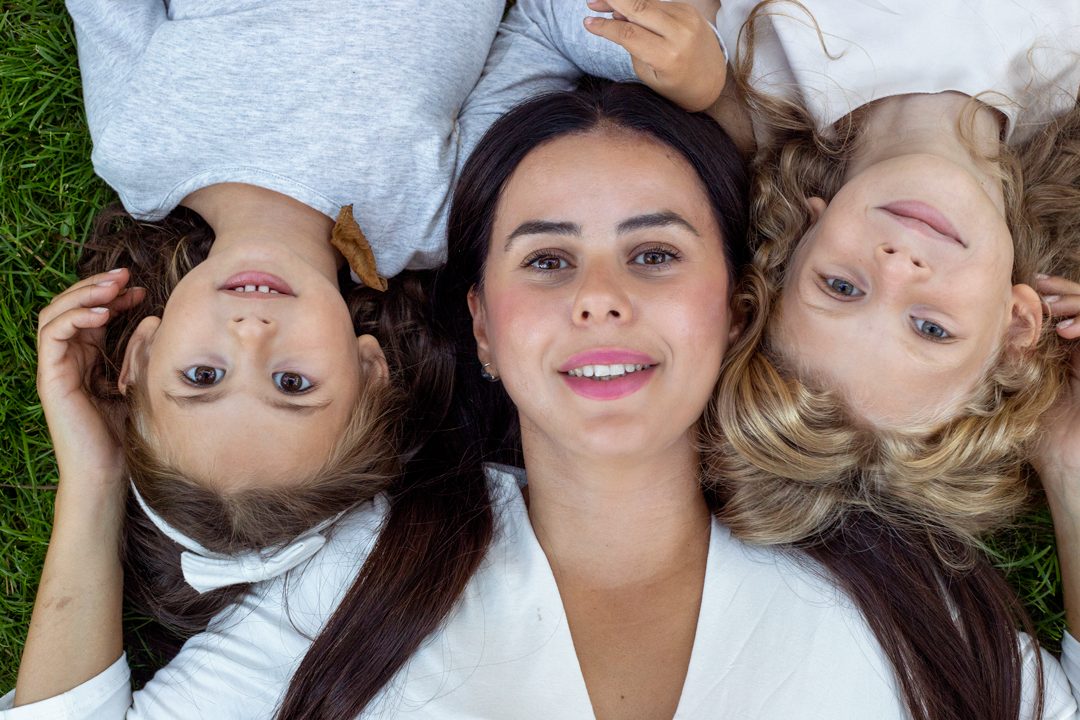 Mother and daughters lying together in the grass