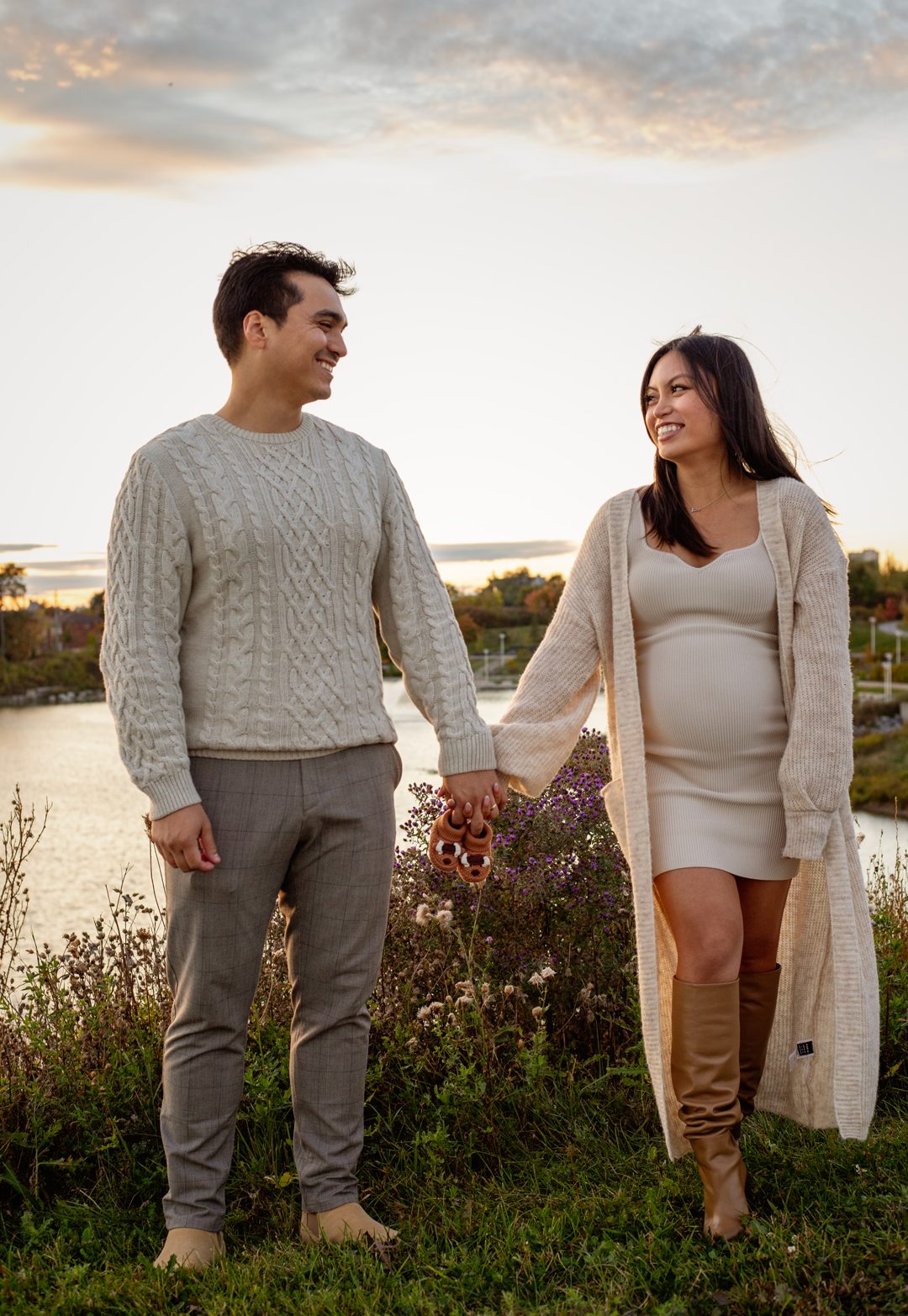 Maternity couple holding hands at sunset