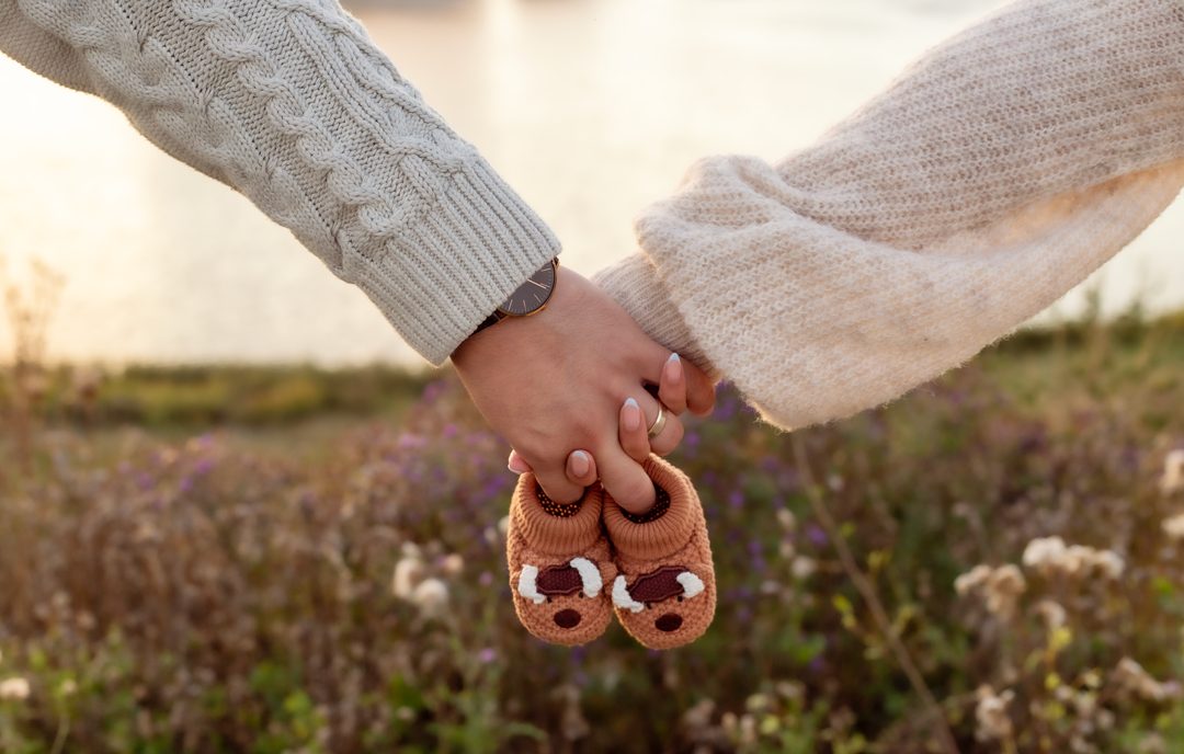 Maternity detail shot, hands holding baby booties