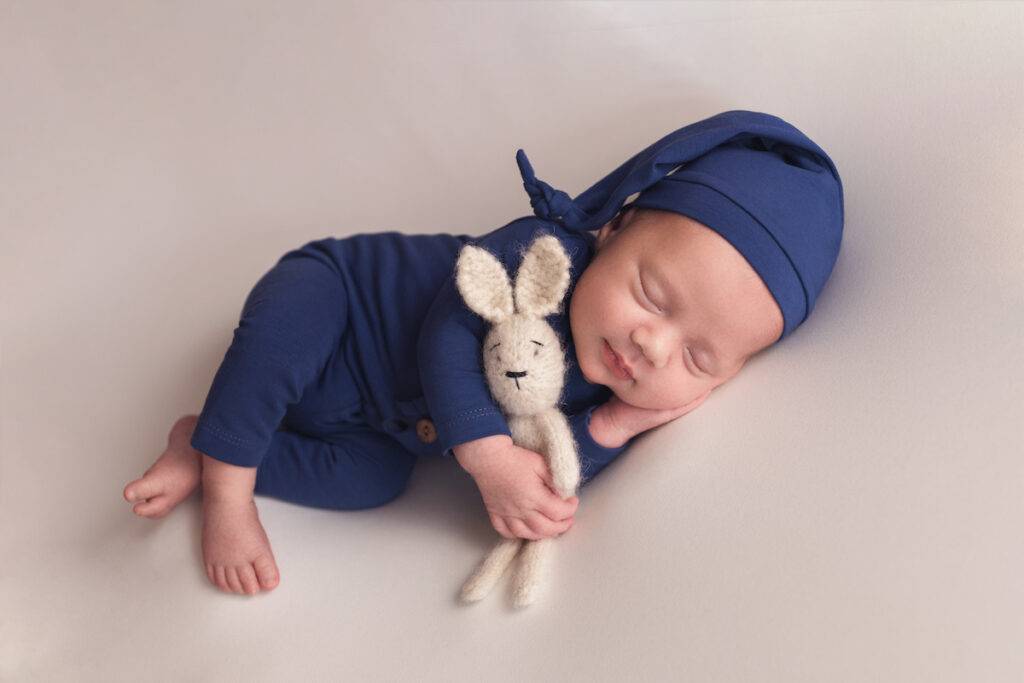 A newborn baby in a blue suit. The first photo session of a newborn.